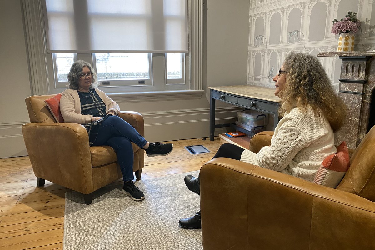 Two people in conversation in the armchairs of a Connexus training room